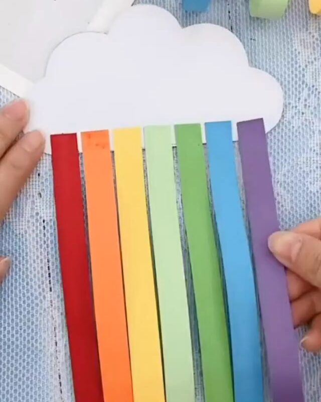 Les bandes de papier aux couleurs de l'arc-en-ciel collées bien droites sous le nuage en papier