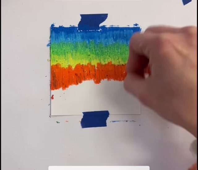 Cartes à gratter, première étape : colorier la feuille en bandes de craie grasse, du bleu au rouge, jusqu'à couvrir tout le papier