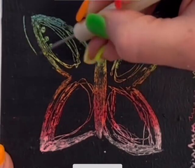 Cartes à gratter maison : un papillon gratté dans la couche noire, dont le trait laisse ressortir le rose, le jaune et le vert de la craie grasse